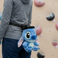A rock climber wearing a Stitch chalk bag at an indoor climbing gym