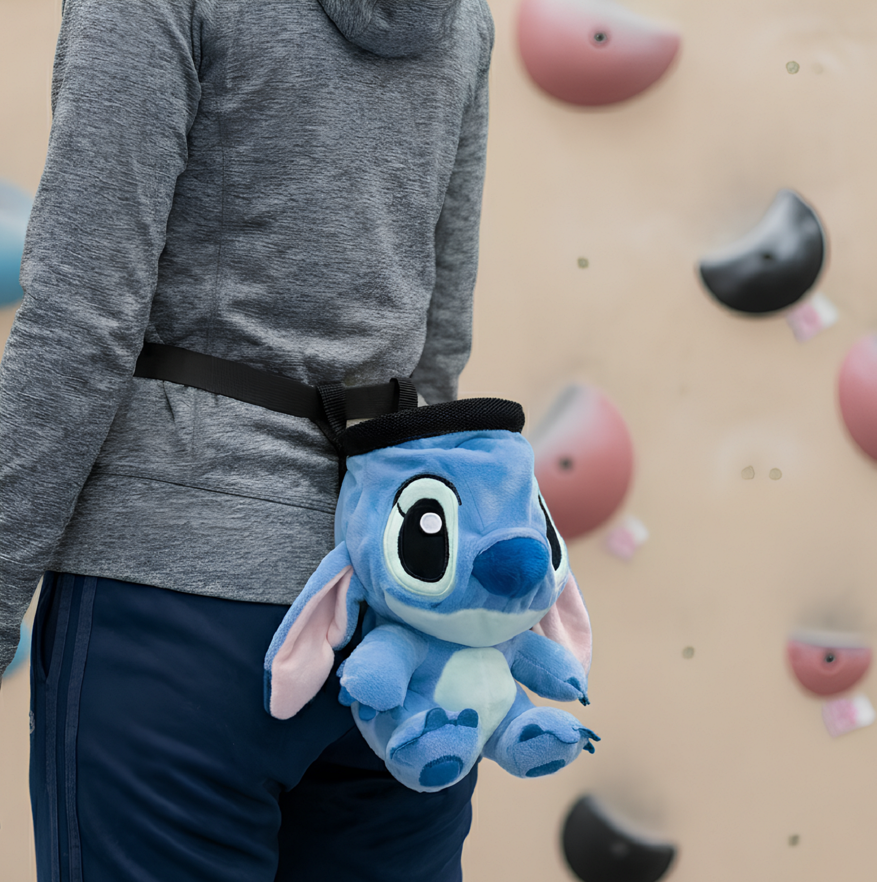 A rock climber wearing a Stitch chalk bag at an indoor climbing gym
